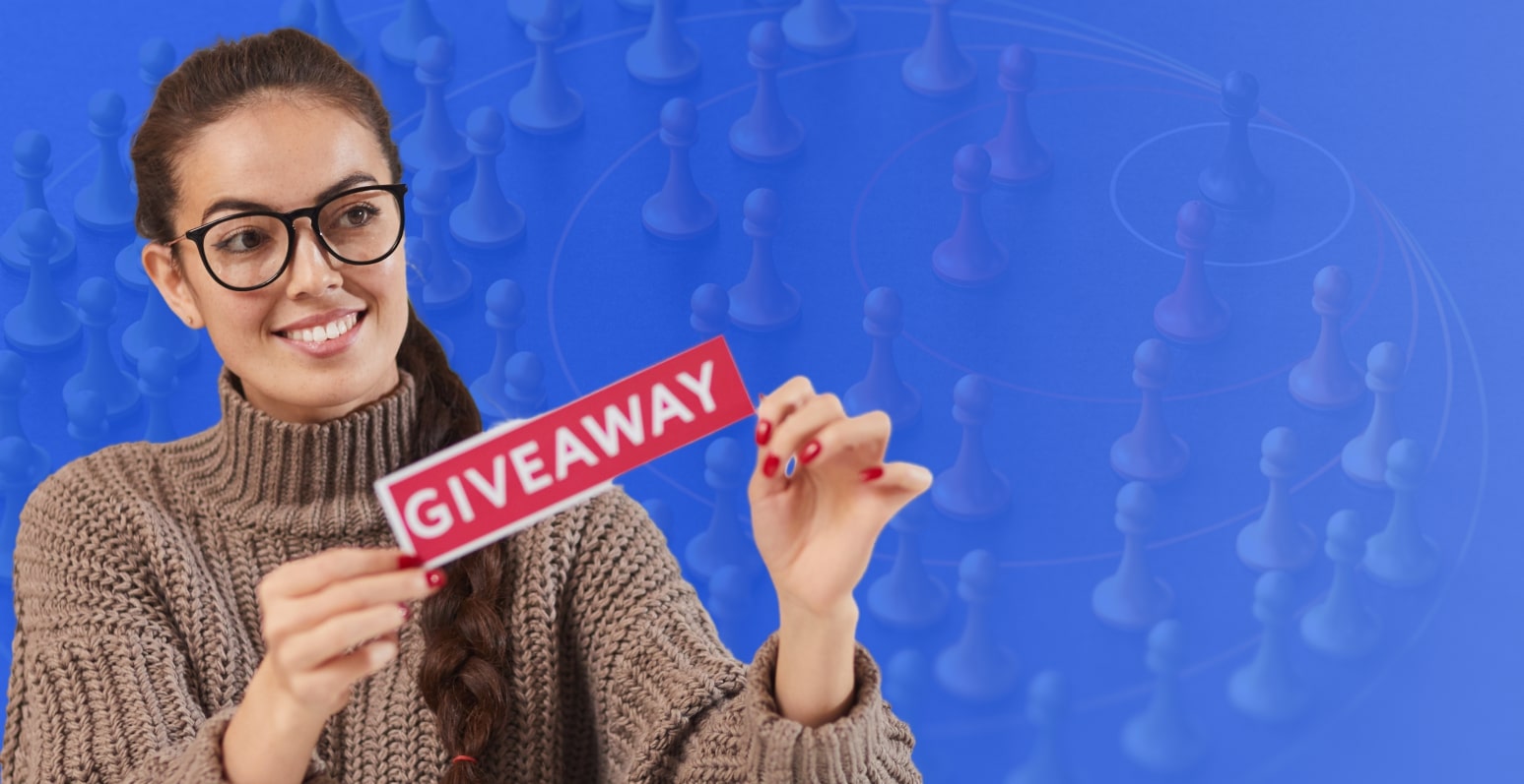 A woman in her 30s is holding with both hands a piece of paper with a red background that reads "GIVEAWAY" in capital letters. She is standing in front of a blue background with chess pieces with very low opacity
